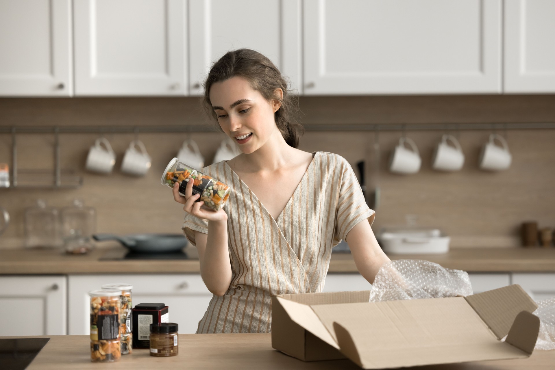 Young woman holding bottle with salty snacks and reading ingredients